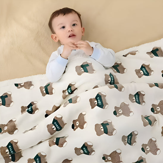 Un bébé couché dans son lit avec une couverture sur lui blanche avec des oursons