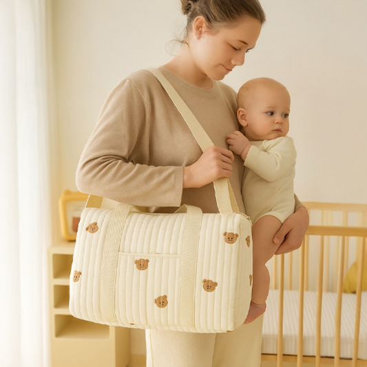 Maman portant son bébé dans ses bras avec un sac a langer à l'épaule avec des motifs ourson