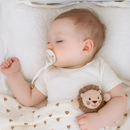 Un bébé couché avec un oreiller dans une doudou avec des cœurs avec une attache tétine en forme de tête de lion