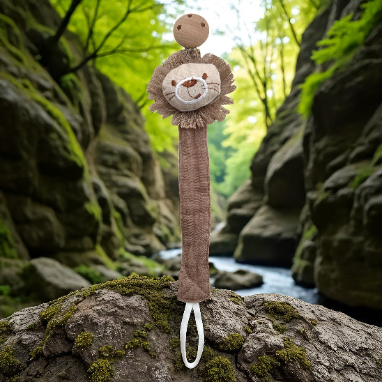 Attache tétine en forme de tête de lion sur une roche devant un ruisseau entre deux montagnes .