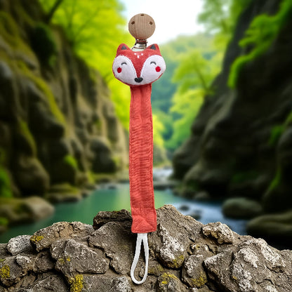 Attache tétine en forme de tête de renard sur une roche devant un ruisseau entre deux montagnes .