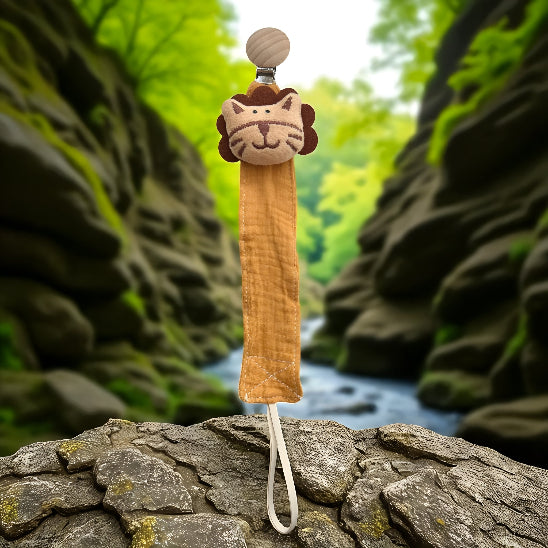  Attache tétine en forme de tête de tigre sur un t’as de roche devant un ruisseau avec un mur de géantes roche. 