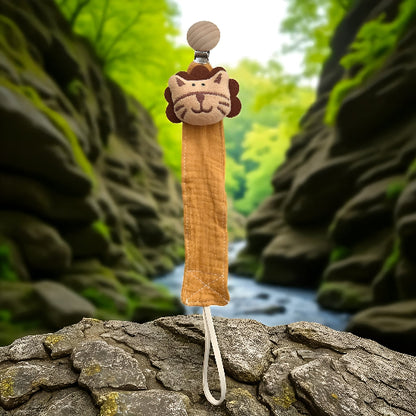  Attache tétine en forme de tête de tigre sur un t’as de roche devant un ruisseau avec un mur de géantes roche. 