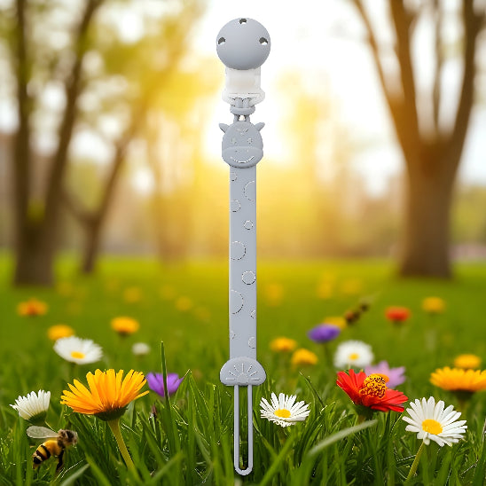 Une attache tétine devant un paysage avec des fleurs de différence couleur et des abeilles avec des arbres