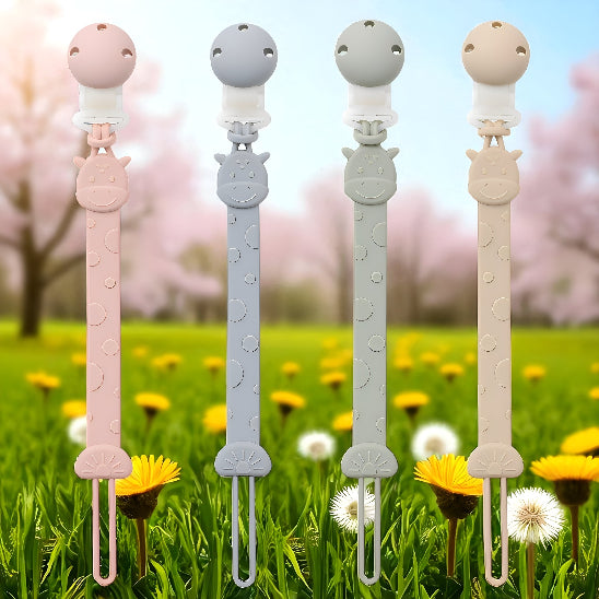 Des attaches tétines devant un paysage avec des fleurs jaunes, blanche et des arbres de feuille rose