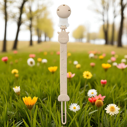 Une attache tétine devant un champ de feuille et des arbres.
