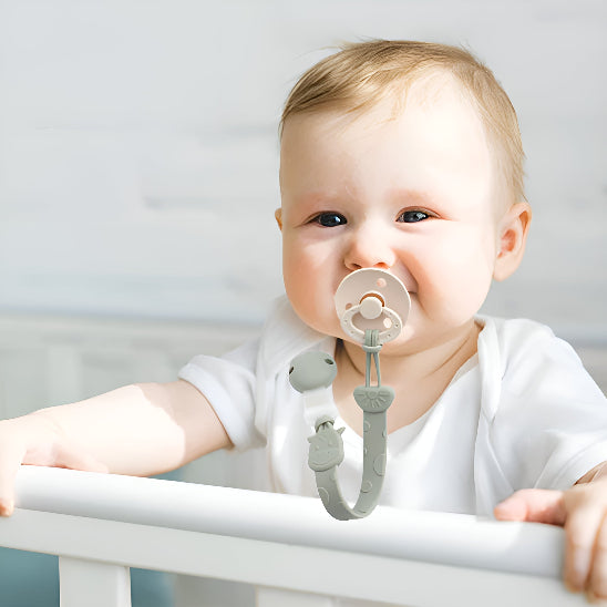 Un bébé dans une couchette avec une attache tétine devant un mur blanc