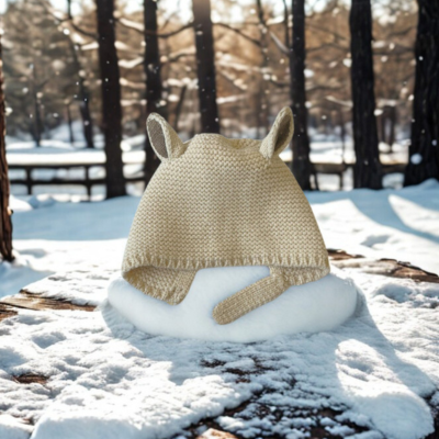 Bonnet bebe beige TricotDouillet™ sur une table en hiver