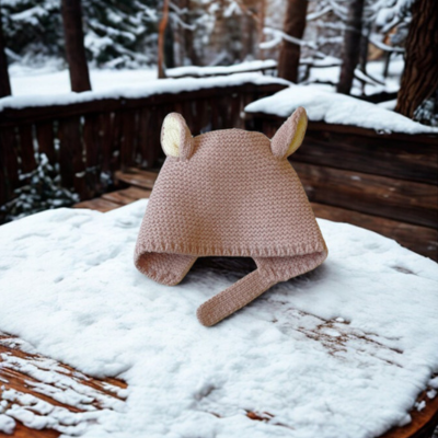 Bonnet bebe rose TricotDouillet™ sur une table en hiver