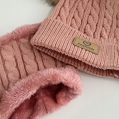 Un bonnet tricot rose sur une table.