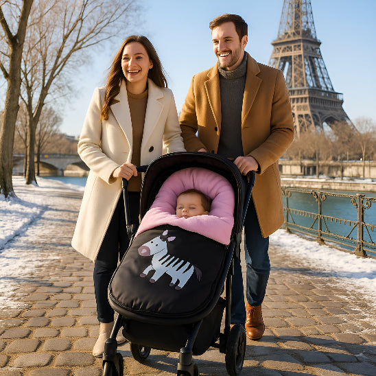 Une maman et un papa marchent dans un parc devant la tour Eiffel en poussant une poussette avec un bébé dans une chanceliere bebe rose.