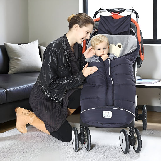 Une maman regarde un enfant dans une chanceliere dans une poussette qui est dans un salon avec un divan et une fenêtre.