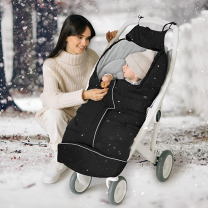 Un bébé dans une chanceliere noir dans une poussette sur la neige et une maman que le regarde avec un sourire.