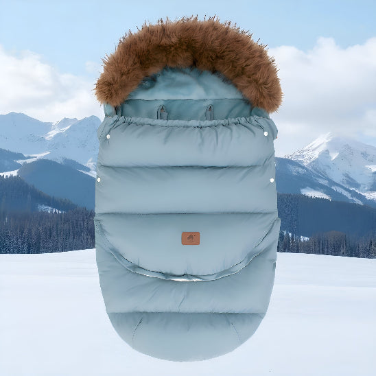 Chanceliere poussette turquoise sur la neige en montagne.