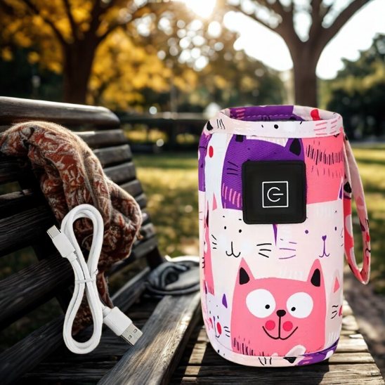 Chauffe biberon nomade rose sur un banc de parc avec un cable USB.