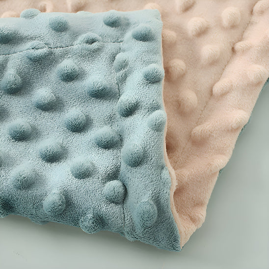 Le coin d'une couverture bleue et rose pliée sur elle-même 