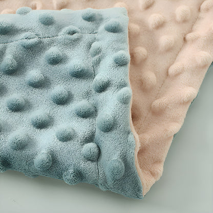 Le coin d'une couverture bleue et rose pliée sur elle-même 