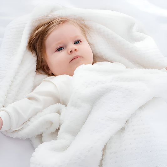Un bébé dans une couverture bébé blanche.