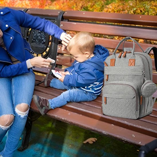 maman bébé assis banc parc sac a langer gris