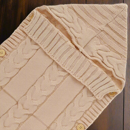 Un nid d'ange bebe beige avec capuchon sur une table en bois.