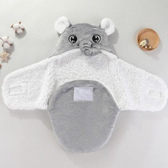 Un nid d'ange gris avec un capuchon en forme de tête d'éléphant sur une table avec des accessoires de décoration.