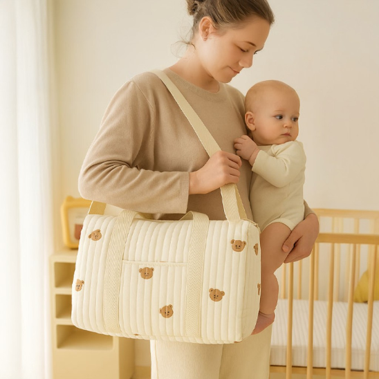Maman portant son bébé dans ses bras avec un sac a langer à l'épaule avec des motifs ourson